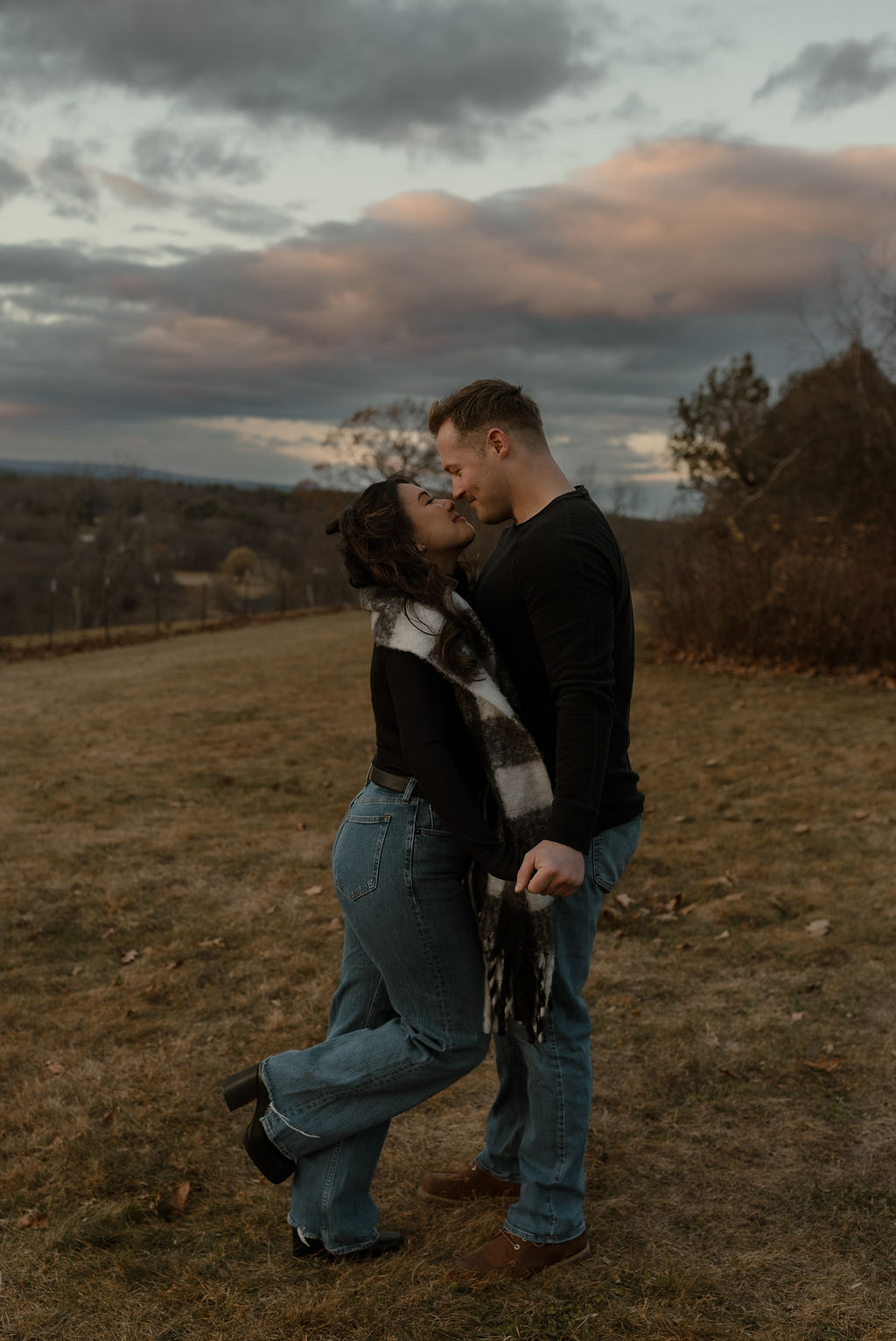 engaged couple holding hands while facing each other outside 