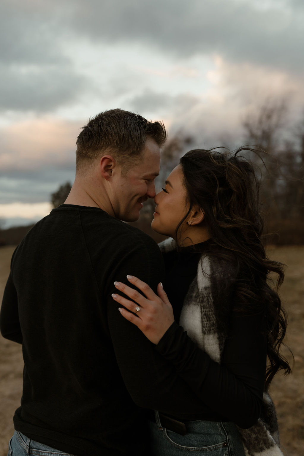 engaged couple hugging and putting their noses together outside in the cold 