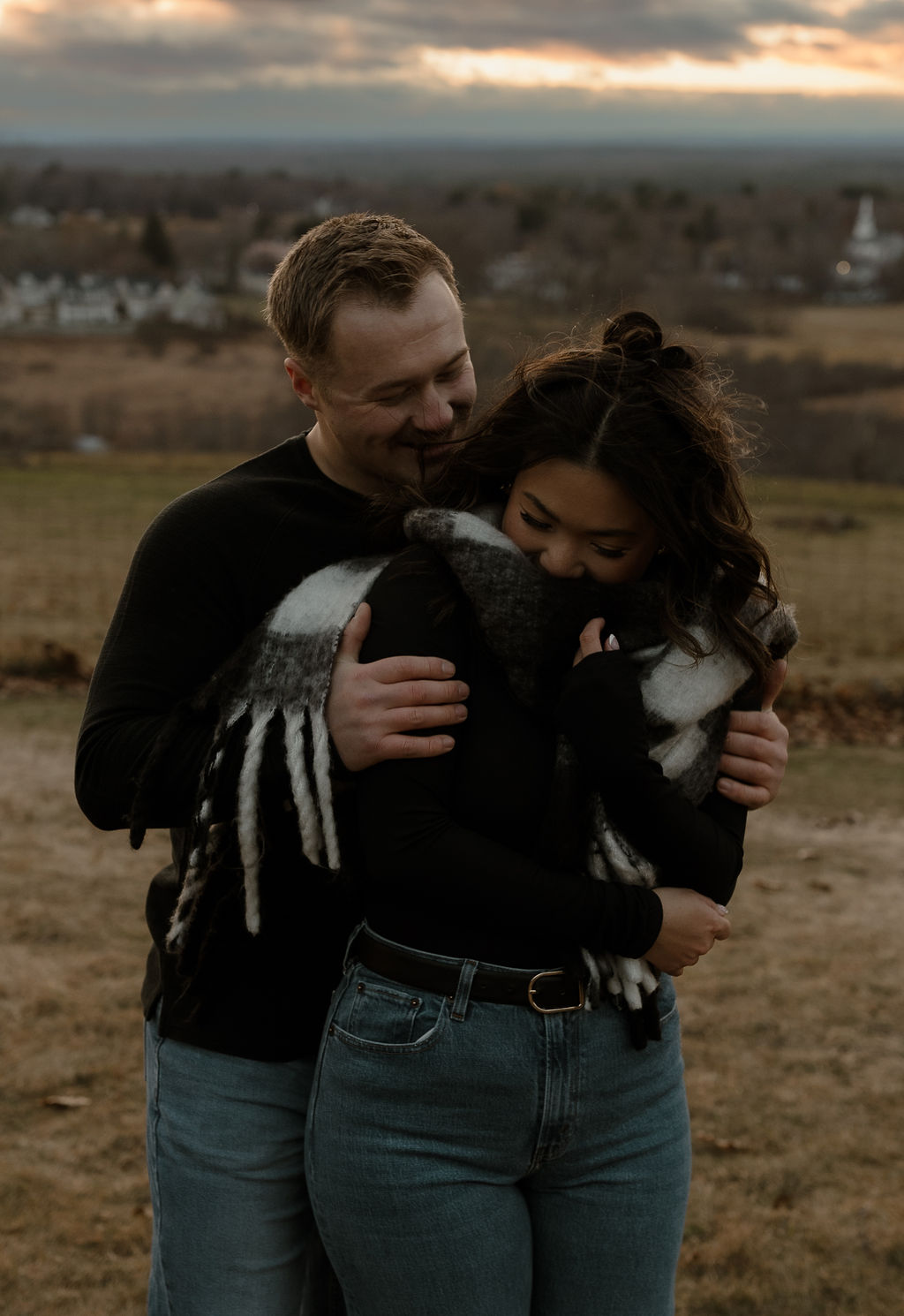 a man hugging a woman from behind during their Massachusetts Engagement Photos