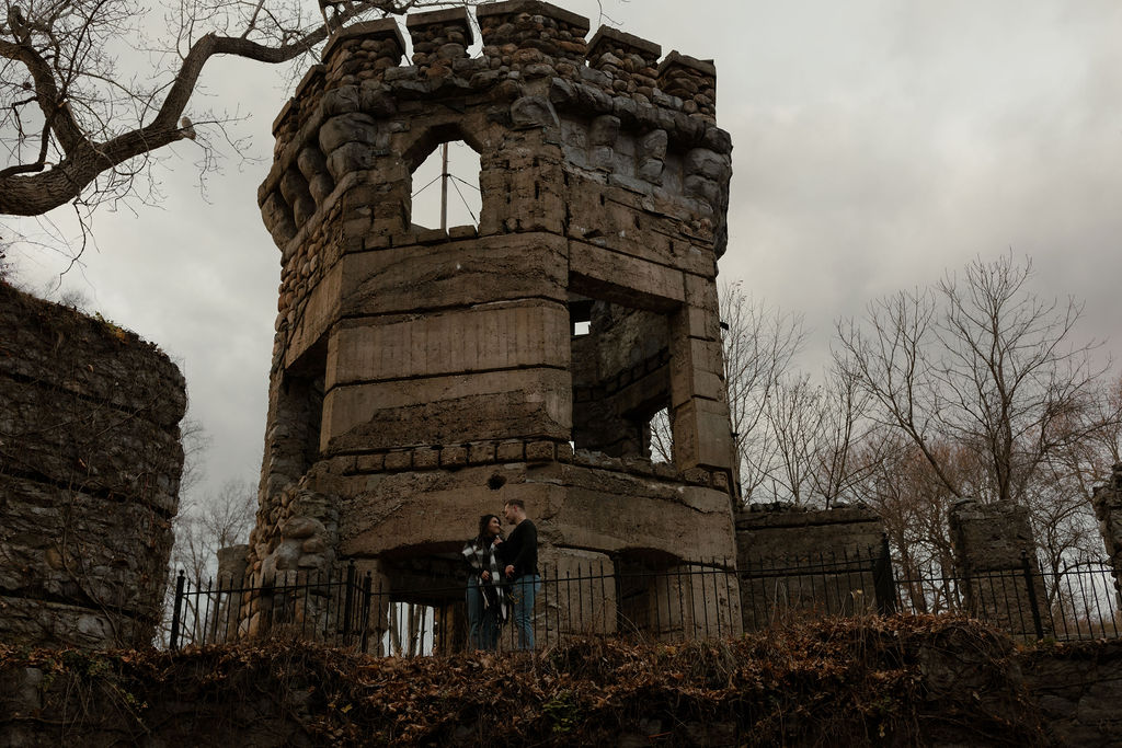 newly engaged couple posing outside of a castle for engagement photos 