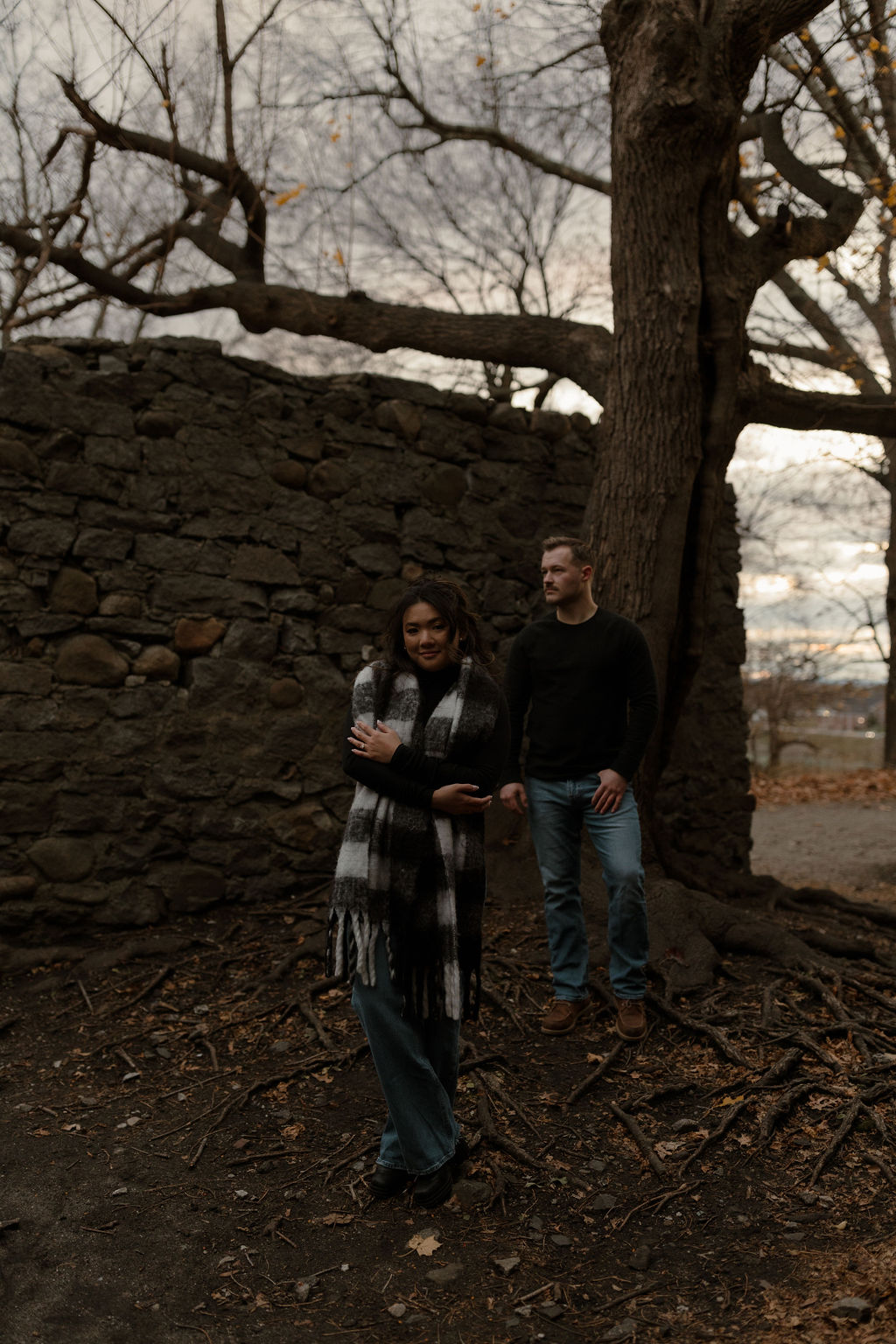 newly engaged couple standing by the castle wall posing for their Massachusetts Engagement Photographer